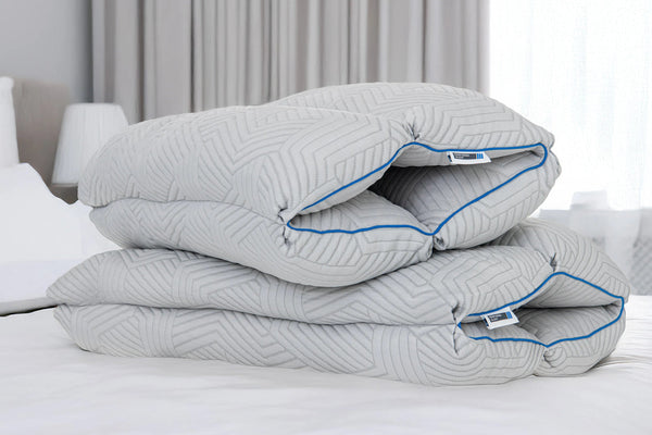 Two PerformaSleep Adjustable Pillows on top of a mattress with white sheets
